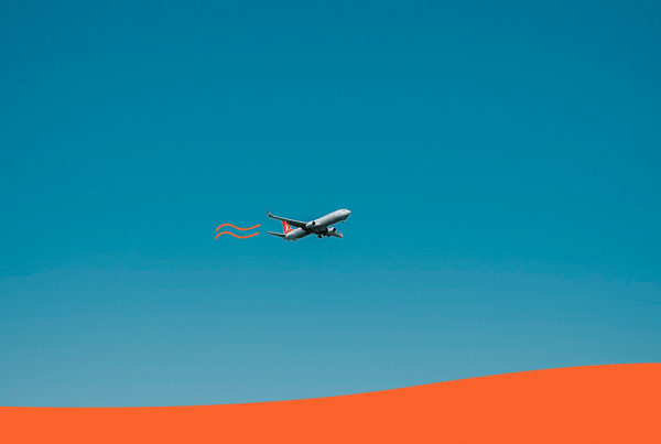 Avión volando sobre un fondo azul y naranja para ilustrar los gastos ocultos de un viaje