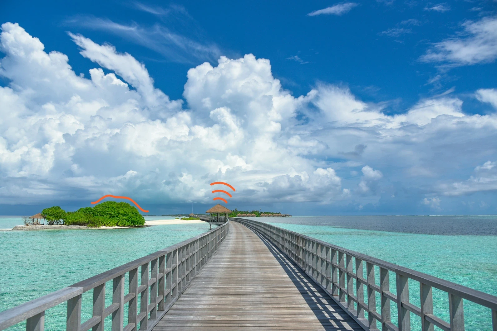 Passerelle en bois au-dessus d’une eau turquoise menant à une île tropicale.